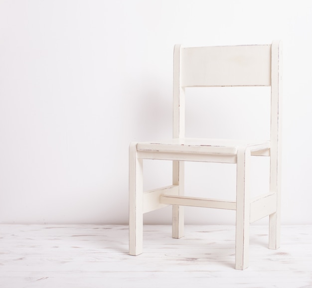 Photo single white rustic chair standing in an empty room on light wooden parquet floor.