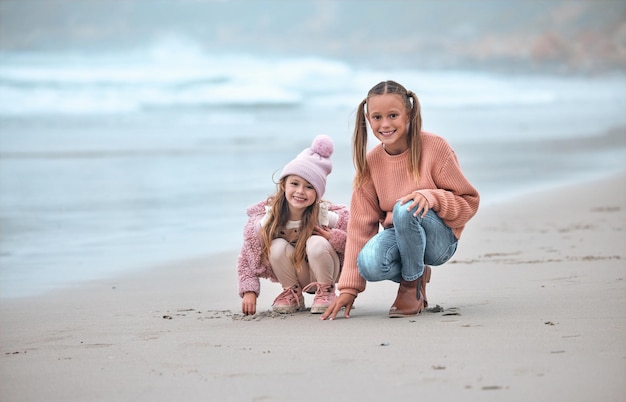 Sisters beach and happy with smile on sand and have fun together being playful joy and cheerful for holidays Portrait siblings or girls at ocean for bonding loving or seaside vacation for break