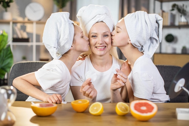 Sisters kissing mother in cheeks during skin care at home