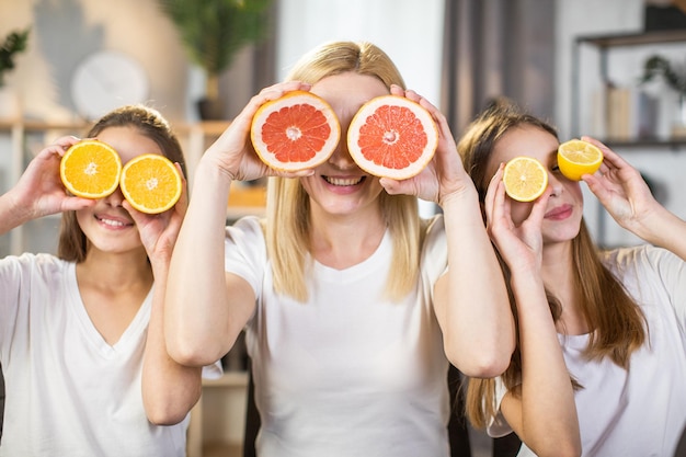 Sisters and mother covering eyes under slices of citrus