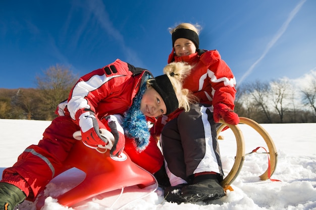 Sisters in snow on toboggan