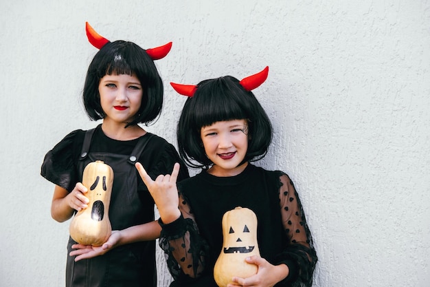 Sisters wearing wig with red horns and black dresses on Halloween celebration party portrait White wall for a background