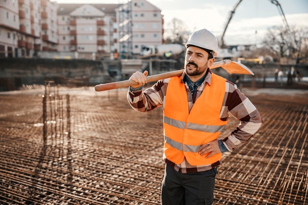 Photo a site worker is holding shovel on shoulder and resting form hard work on reconstruction area