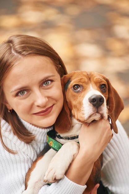 Sitting holding animal and looking into the camera Young woman is with her dog in the park