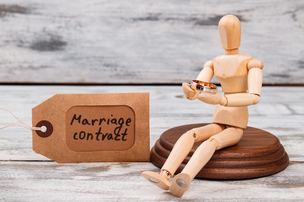 Sitting mannequin holding wedding ring. Marriage contract concept.