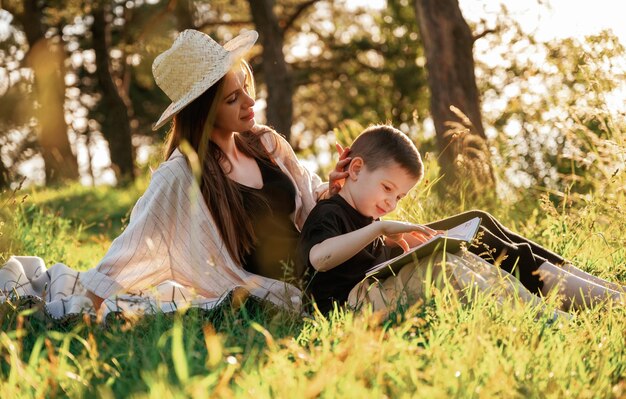 Sitting and reading the book Mother and son are in the forest together