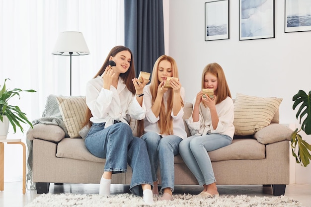 Sitting on the sofa Young mother with her two daughters at home at daytime