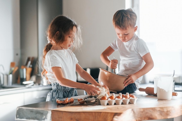 Sitting on the table Little boy and girl preparing Christmas cookies on the kitchen