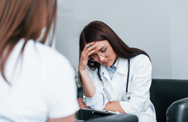 Sitting and talking Young woman have a visit with female doctor in modern clinic