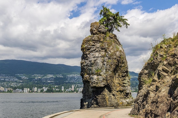 Siwash Rock Stanley Park Seawall  sunny day with white clouds over North Vancouver British Columbia