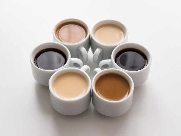 Six different cups of coffee on a white table. The view from the top. White coffee set