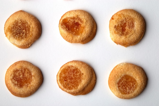 Six handmade cookies with apricot jam arranged in even rows isolated on white background