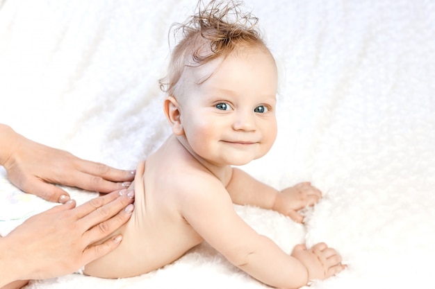 Six-month-old baby receiving a back massage from a female masseur