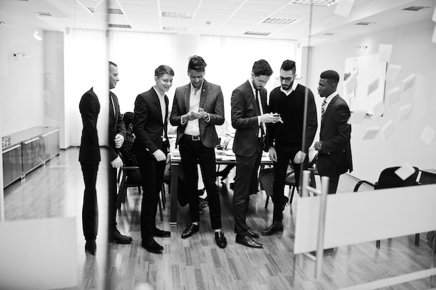 Six multiracial business mans standing at office and use mobile phones Diverse group of male employees in formal wear with cellphones