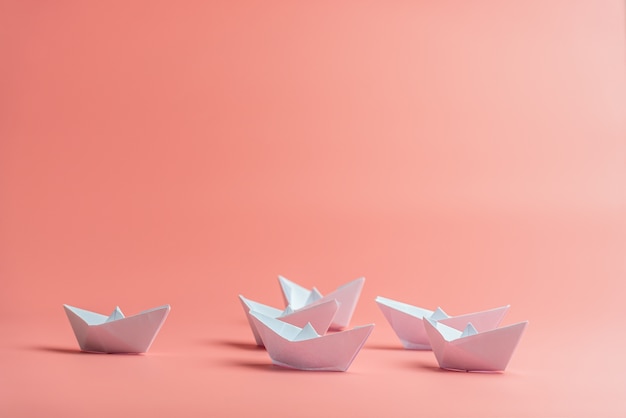 Six origami paper boats over pink background.