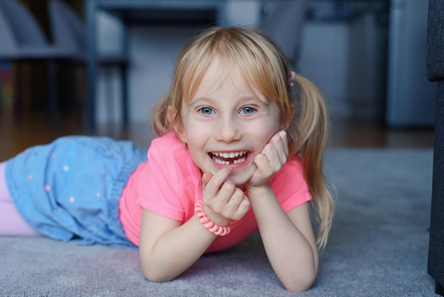 Six year smiling happy girl holding a first fallen tooth and looking at him