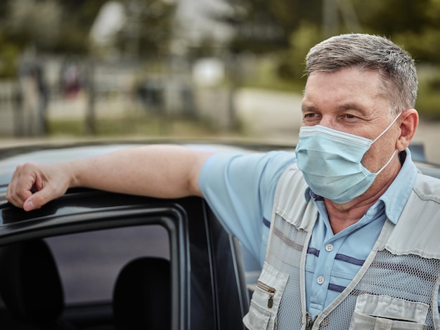 Sixtyyearold man in a medical mask near the car