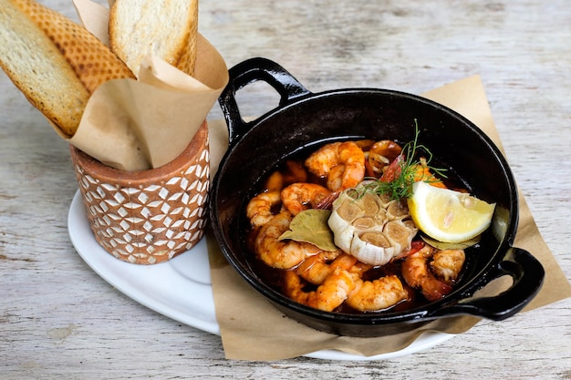 Sizzling Gambas Al Pil Pil with garlic bread served in a dish isolated on grey background side view of snacks