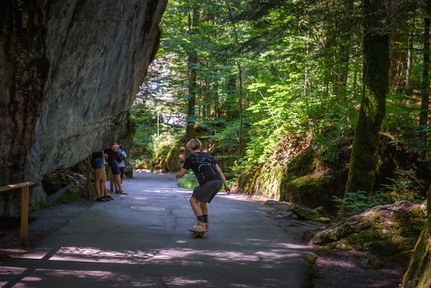 Skater riding a skateboard on a road towards the blausee lake in switzerland