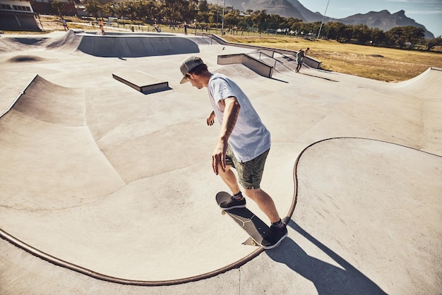 Skater sports and man at skate park in city performing action trick or stunt Fitness skateboarding and young male skateboarder on ramp training practice or workout outdoors in town for exercise