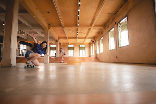 Skater woman person playing skateboard in sport gym young Asian woman are happy and fun with skateboarding lifestyle in city teenage hipster female trendy fashion