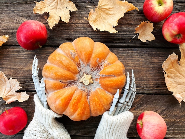 skeleton hands holding a ripe orange pumpkin