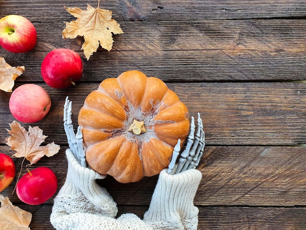 skeleton hands holding a ripe orange pumpkin