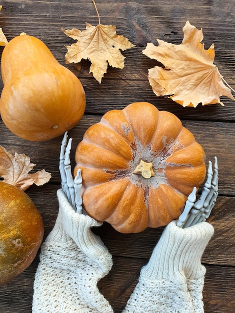 skeleton hands holding a ripe orange pumpkin