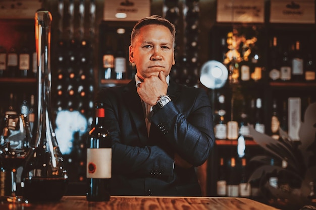 Skeptical elegant wine sommelier is ready to try new red wine at artisan wine boutique.