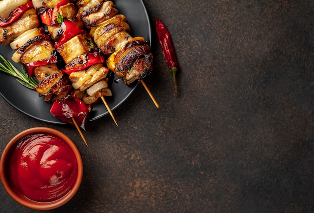 Skewers of meat with grilled vegetables on a plate on a stone background