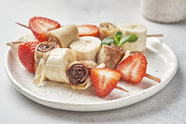 Skewers of pancakes crepes with nut butters and fruits