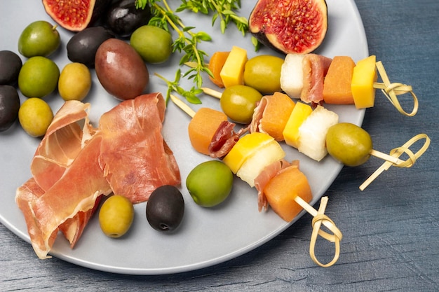 Skewers with olives cheese and melon on a gray plate