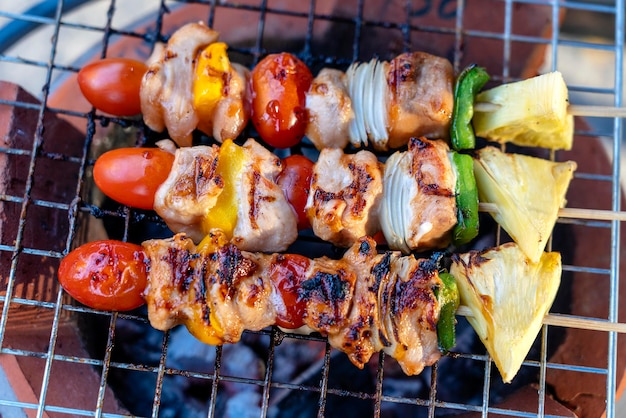 Skewers with pieces of grilled barbecue green bell pepper red tomato and meat for sell in street market Thailand closeup