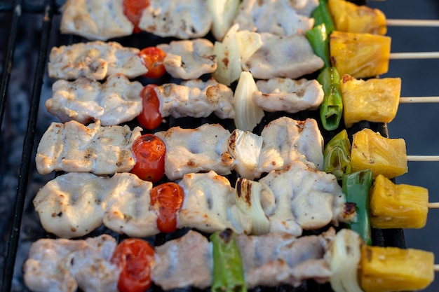 Skewers with pieces of grilled barbecue green bell pepper red tomato and meat for sell in street market Thailand closeup