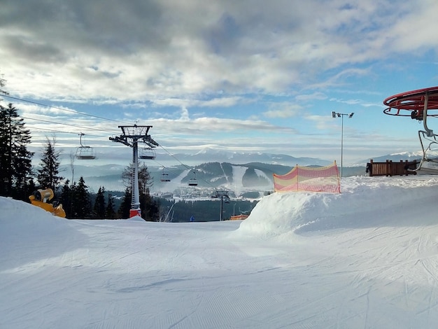 Ski lift over snow covered field against sky