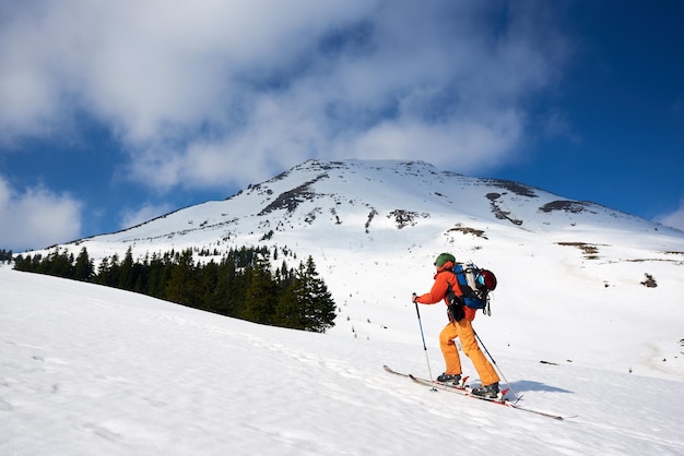 Ski touring man reaching the top in spectacularly snowy mountains at sunny day