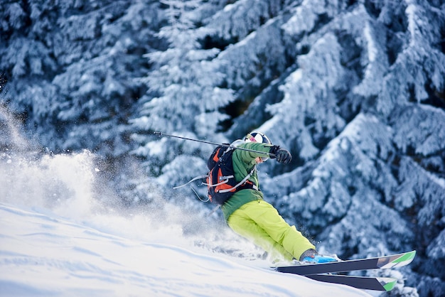 Skier backpacker skiing down on slope raising blizzard snow powder