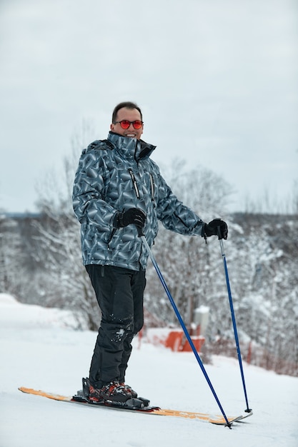 A skier in gray jacket is riding downhill the slope on a frosty day