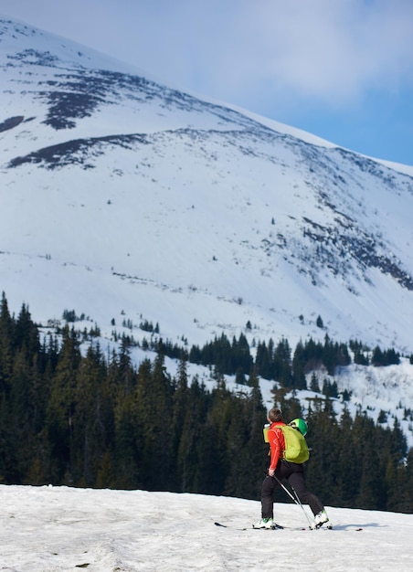 Skier hiker with backpack on skis in deep white snow on background of beautiful winter landscape