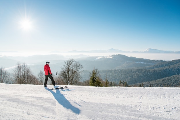 skier resting after the ride standing on top of the ski slope