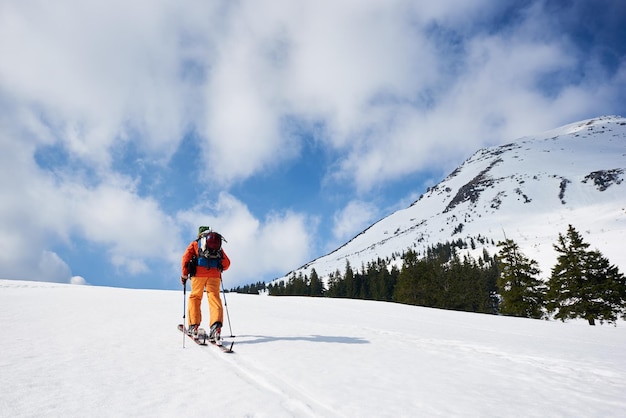 Skier tourist with backpack on background of bright blue sky and beautiful mountain panorama