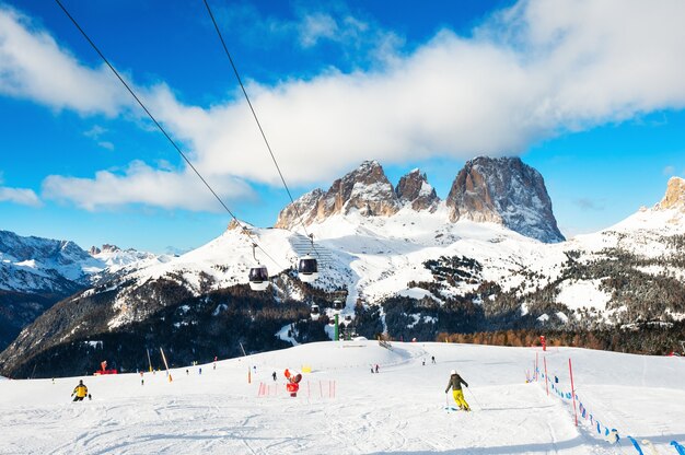 Photo skiers skiing down the slope in ski resort in winter dolomite alps. val di fassa, italy.