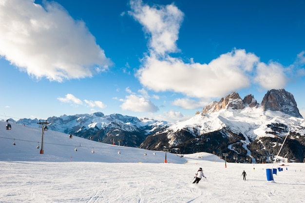 Skiers skiing down the slope in Val Di Fassa ski resort in Dolomites, Italy. Winter landscape