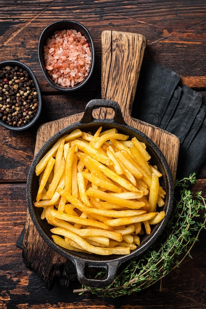 Skilet full of Potato french fries with salt Wooden background Top view