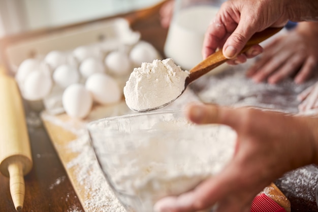 Skilled baker holding a spoonful of flour for making dough