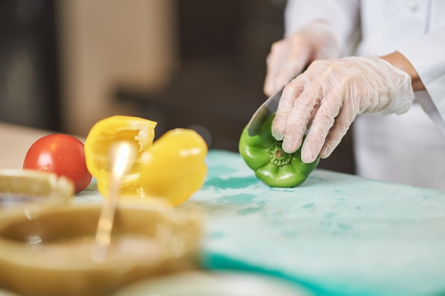 Skilled chef cutting a fresh juicy green pepper