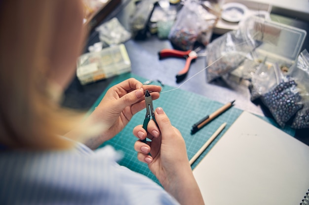 Skilled employee using a tool and cutting a wire for a jewel product