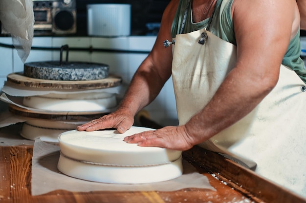 Skilled hands of an alpine dairyman prepare local cheese