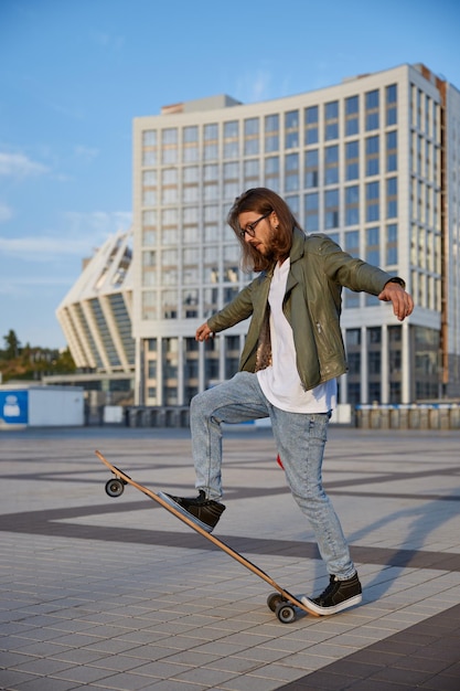 Skilled hipster guy making stunt on skateboard riding fast