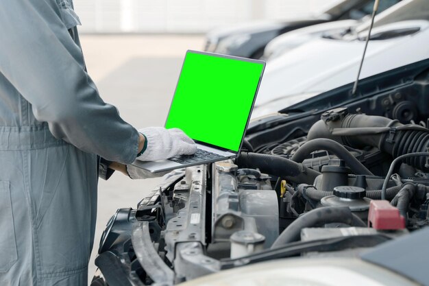 Photo skilled mechanic using a laptop computer green screen to check collect information during work